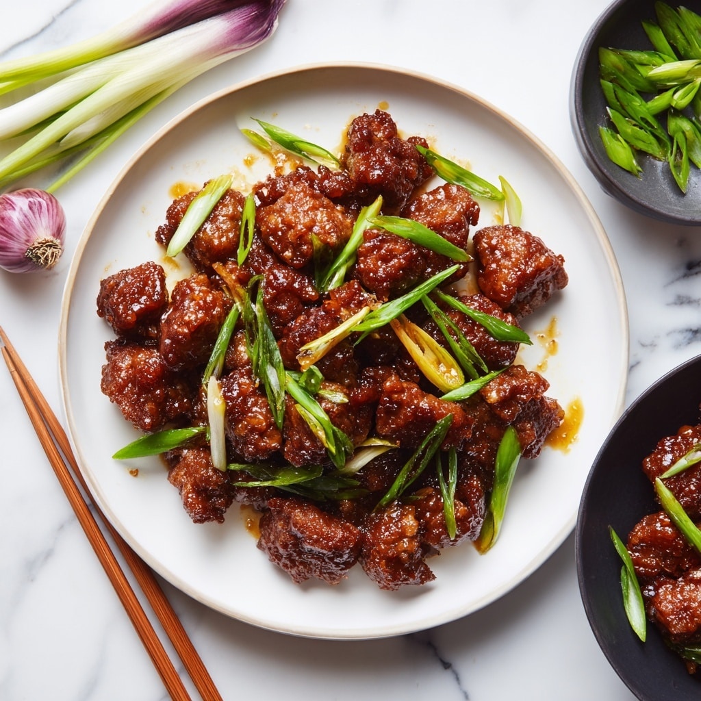A white plate is filled with several pieces of glazed brown meat that look crispy and sticky, each piece coated evenly with shiny sauce. Bright green chopped scallions are scattered on top, adding a fresh look with some long and some small slices. At the edge of the plate, a pair of light wooden chopsticks rest partly on the plate and partly on the white marbled surface beneath. Above the plate, a few extra chopped green onions and a whole light purple shallot lie on the white marbled background. To the right, a black bowl contains more glazed meat with a couple of green onion pieces as garnish. The overall setting feels casual and homemade. photo taken with an iphone --ar 4:5 --v 7
