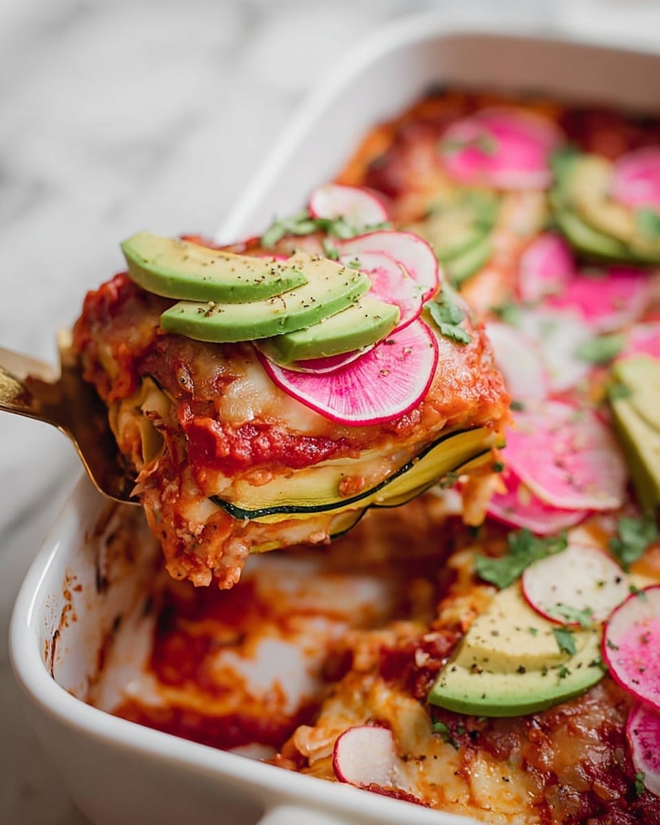 The image shows a close-up of a slice of a baked zucchini lasagna being lifted from a white baking dish on a white marbled surface. The slice has several visible layers: a thin greenish-yellow zucchini slice on top, followed by a bright red tomato sauce layer with a smooth texture, and underneath, more layers of zucchini and sauce mixed with a creamy filling. On top of the slice are fresh toppings including sliced radishes in pale pink and white, pink pickled onion curls, and green avocado slices sprinkled with black pepper and small leaves of cilantro. A woman's hand holding a gold spatula lifts the slice, revealing a slightly messy but appetizing edge of the dish. The entire scene is warm and inviting. photo taken with an iphone --ar 4:5 --v 7