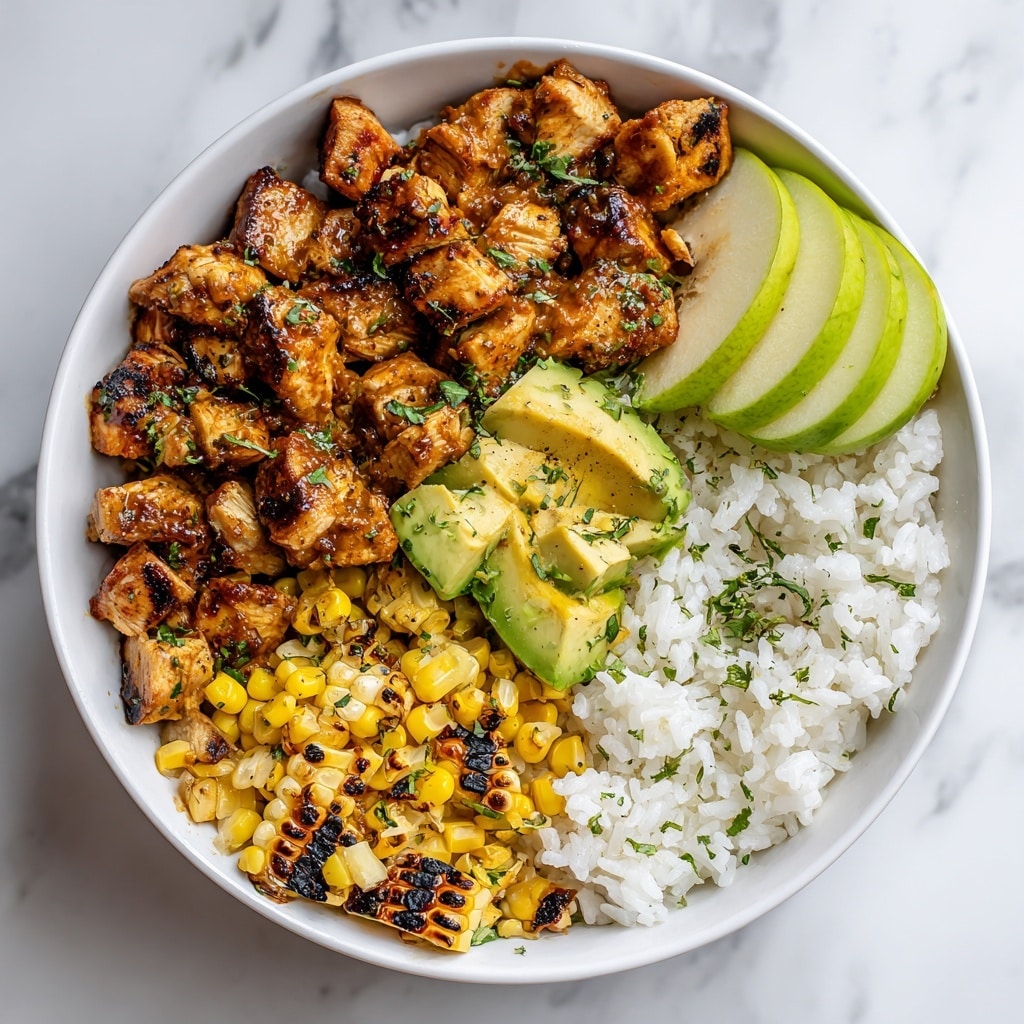 The image shows a white bowl filled with a colorful honey chipotle chicken rice bowl placed on a white marbled surface. Inside the bowl, the base layer is fluffy white rice on the right side with some green herbs sprinkled on top. Next to the rice, there is a layer of diced grilled chicken pieces coated in a honey chipotle sauce, giving them a shiny golden-brown color and slightly charred edges. Alongside the chicken, there are pieces of charred corn with black grill marks and scattered small yellow corn kernels mixed in. Fresh diced avocado chunks are placed near the chicken and corn, adding a light green color and soft texture. Two thin green apple slices rest on the right side on top of the rice. The bowl shows a clean mix of textures and warm colors, with the grilled chicken and corn contrasting the creamy green avocado and the bright white rice. Photo taken with an iphone --ar 4:5 --v 7