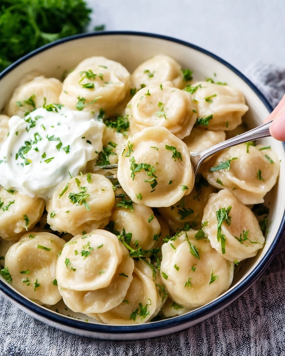 A bowl filled with two layers of round, plump dumplings that have a smooth, pale beige dough surface and are arranged closely together. The dumplings are topped with chopped bright green herbs scattered evenly across them, adding a fresh touch. On the upper left side of the bowl, there is a dollop of thick white sour cream sitting on top of the dumplings. The bowl is white with a thin dark rim and rests on a white marbled surface with a textured cloth underneath. A silver fork is lifting one dumpling from the right side of the bowl, held by a woman's hand. Photo taken with an iphone --ar 4:5 --v 7
