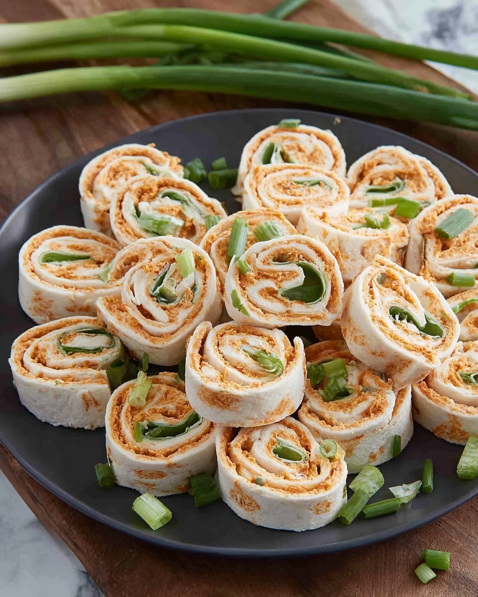 A dark gray plate holds many small rolled pinwheel sandwiches cut into thick slices, showing three visible layers: a white outer tortilla wrap, a creamy orange filling with a slightly rough texture, and a thin green layer of sliced scallions inside. The rolls are neatly stacked and scattered with extra small pieces of chopped green scallions on top and around the plate. The plate sits on a wooden surface with whole green scallions in the background, but the wood surface is changed to a white marbled texture. photo taken with an iphone --ar 4:5 --v 7