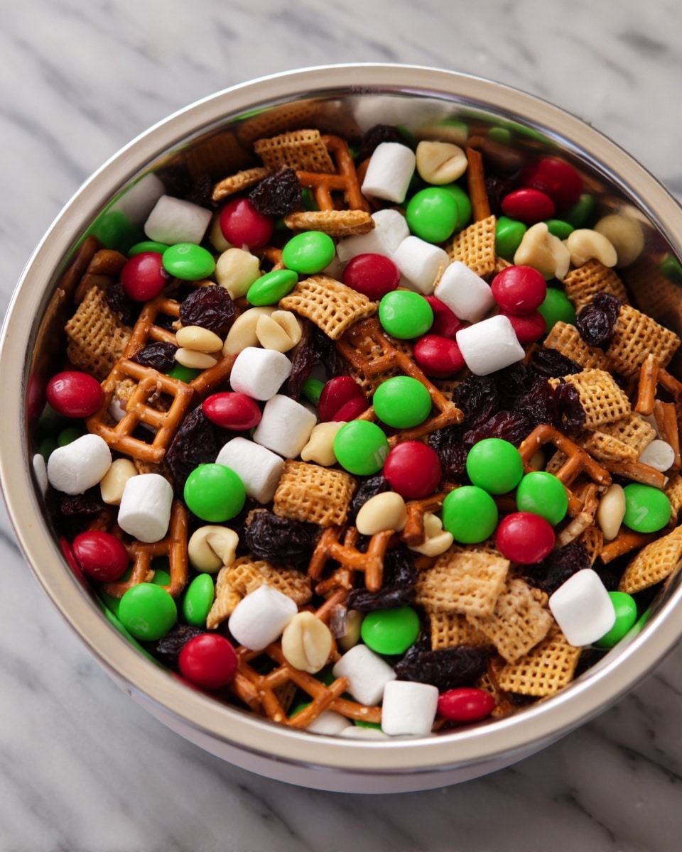Inside a white bowl with a metal rim, there is a mix of small snack items. The mixture has light brown pretzel squares with a crunchy texture, creamy off-white peanuts, soft white mini marshmallows, dark wrinkled raisins, and bright red and green candy-coated chocolates scattered all over. These ingredients are evenly spread in one layer, showing a colorful and textured snack mix. The bowl is placed on a white marbled surface. photo taken with an iphone --ar 4:5 --v 7
