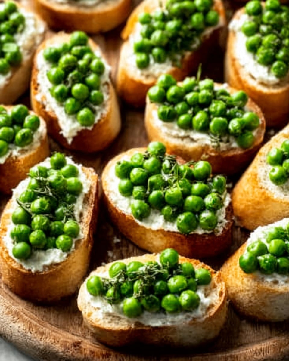 Several pieces of toasted baguette slices are arranged closely on a wooden board. Each slice has a thick layer of white creamy cheese spread on top, with a generous pile of bright green peas covering the cheese. The peas add a fresh, slightly bumpy texture to the smooth cheese, and the bread's golden-brown crust contrasts with the white and green toppings. There is a woman's hand reaching toward one of the toasts. The background is a white marbled texture. Photo taken with an iphone --ar 4:5 --v 7