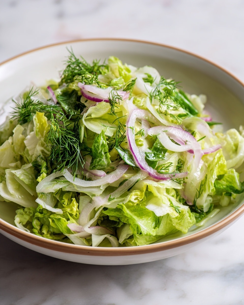 The image shows a close-up view of a fresh green salad in a white bowl with a light brown rim. The salad has roughly three layers: the bottom layer is a bed of shredded green lettuce with a slightly wrinkled texture; the middle layer includes thinly sliced pale green and light purple onion pieces; the top layer is chopped fresh herbs like parsley and dill, adding a mix of bright green colors and fine textures. The salad looks crisp and vibrant against the white marbled background. Photo taken with an iphone --ar 4:5 --v 7
