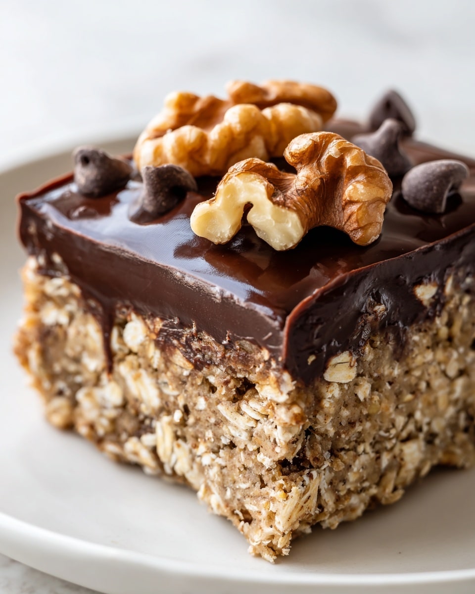 A close-up view of a square oat bar with two distinct layers: the bottom layer is thick and textured, made of oats and small bits of chocolate, showing a grainy, natural beige and dark brown pattern; the top layer is a smooth, glossy, rich dark chocolate coating that spreads evenly across the oat base and drips slightly over the sides. On top of the chocolate layer, there are scattered pieces of walnut halves and several chocolate chips, adding rough, irregular shapes and a mix of light brown and dark brown contrast to the shiny surface. The oat bar is placed on a white plate with a soft white marbled texture background. photo taken with an iphone --ar 4:5 --v 7
