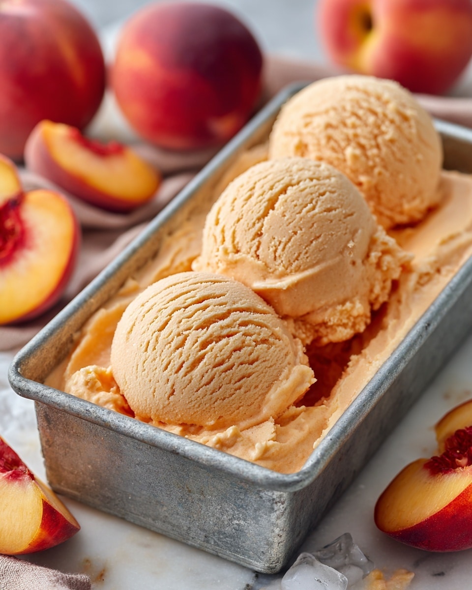 A golden brown peach cake baked in a rectangular metal pan with a slightly worn look. The cake has a soft, slightly cracked top layer with a light dusting of powdered sugar. Five slices of fresh peach are placed in a neat line down the middle of the cake, their bright orange and reddish edges contrasting with the creamy, pale cake surface. The pan sits on a wooden board next to several whole peaches with a soft fuzzy texture. The background features a white marbled surface with a beige cloth casually placed nearby and a wooden spatula on the side. Photo taken with an iphone --ar 4:5 --v 7