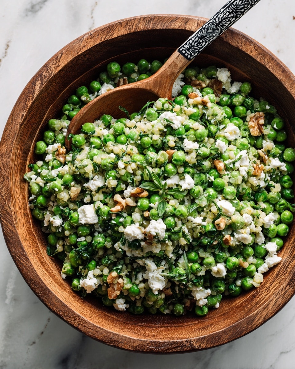 The image shows a white bowl filled with a cucumber feta salad. The bottom layer consists of thinly sliced cucumber rounds that are pale green with darker green edges, arranged evenly across the bowl. Scattered on top are small chunks of white feta cheese, some pieces crumbly and others slightly larger. Interspersed among the cucumbers and feta are thin slices of light purple onion. Light green herbs are sprinkled over everything, and a fresh lemon Greek vinaigrette lightly coats the salad, giving it a slight shine. The bowl sits on a white marbled surface, and a woman's hand is gently holding the bowl's edge. photo taken with an iphone --ar 4:5 --v 7