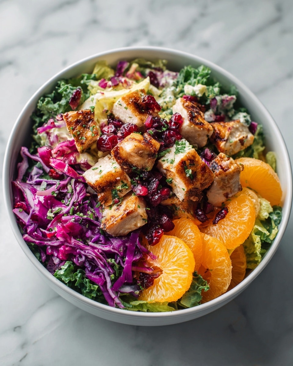 The dish shows a bowl filled with a colorful salad, starting with a base layer of mixed green and purple cabbage leaves that add bright green and deep purple colors and a crisp texture. On top of this are several large pieces of white cooked chicken breast, cut unevenly with a soft, juicy look. Scattered around the salad are small, round, bright red dried cranberries that add pops of color. There are also thin orange slices placed around the edges, adding a fresh, juicy look with bright orange color. Small green leaves, possibly cilantro, are sprinkled over the top, adding a fresh, leafy texture. The bowl is white and sits on a white marbled surface. photo taken with an iphone --ar 4:5 --v 7