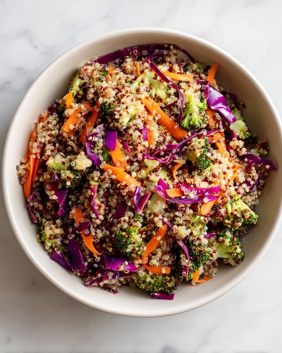 A white bowl filled with a colorful quinoa salad that has three main layers mixed together: small round grains of red and white quinoa with a soft texture form the base, thin shredded orange carrot strips add a crunchy texture, and small chunks of light green broccoli florets mixed with thin slices of bright purple cabbage add freshness and color contrast. The bowl is set on a white marbled surface with soft natural light showing the detailed textures of the salad. photo taken with an iphone --ar 4:5 --v 7