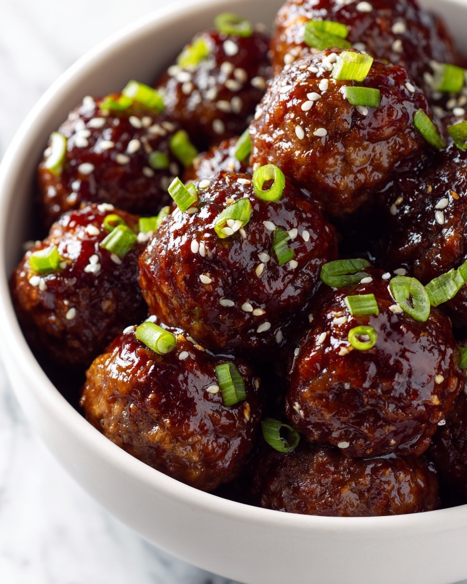 A close-up view of many meatballs in one layer, each coated in a thick, glossy dark brown sauce that gives a shiny look. On top of the meatballs are small, bright green pieces of chopped scallion, adding a fresh pop of color. There are also small white sesame seeds scattered across the meatballs and sauce. All the meatballs rest in a round white bowl with a smooth edge, set on a white marbled surface. The image shows good lighting highlighting the shine and texture of the sauce on the meatballs. photo taken with an iphone --ar 4:5 --v 7