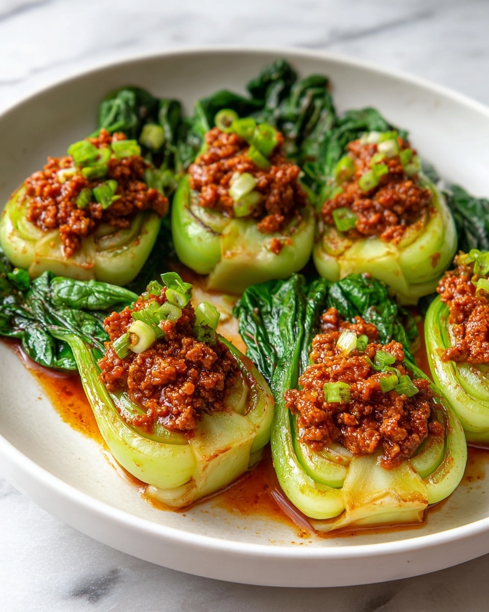 The image shows a black pan filled with six bright green bok choy halves arranged in a circular pattern. Each half is topped with a thick, rich dark red sauce mixed with minced meat and small bits of green onion, giving a textured and juicy look. The bok choy has a shiny, glazed texture where the sauce touches, and the stems are light green and slightly translucent while the leaves are darker and fresh. The pan sits on a white marbled surface. Photo taken with an iphone --ar 4:5 --v 7