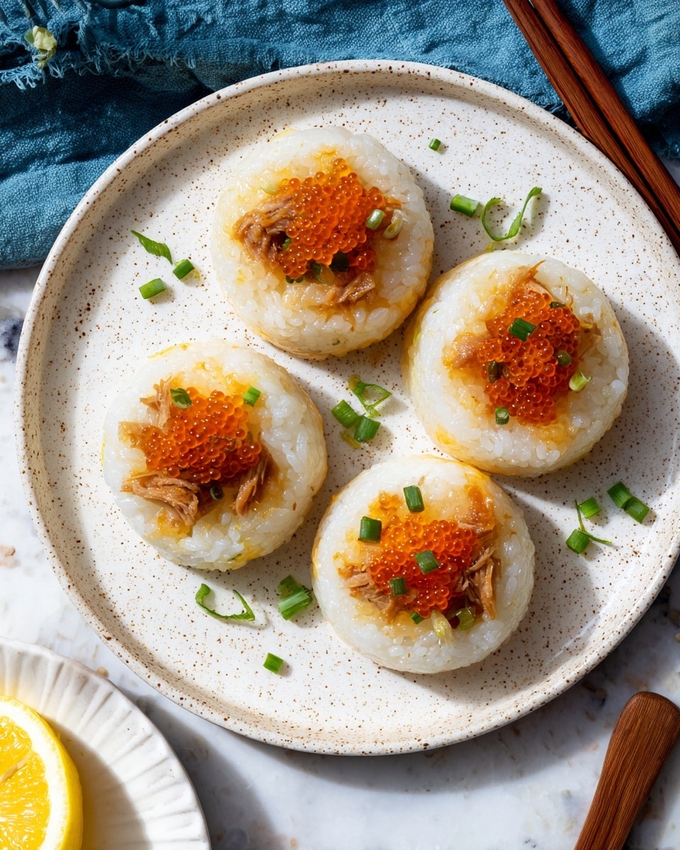 The image shows a white speckled round plate with four small rice cakes placed evenly in a circle. Each rice cake has a pale yellow base of sticky rice, topped with shredded light brown cooked meat. On top of the meat, there is a small heap of orange sauce or roe with a shiny, slightly wet texture, and small round green chopped spring onion pieces are scattered on and around each cake. The plate rests on a white marbled surface with a wooden chopstick and a blue cloth napkin on one side. A part of a white plate with a lemon wedge is visible in the corner. Photo taken with an iphone --ar 4:5 --v 7
