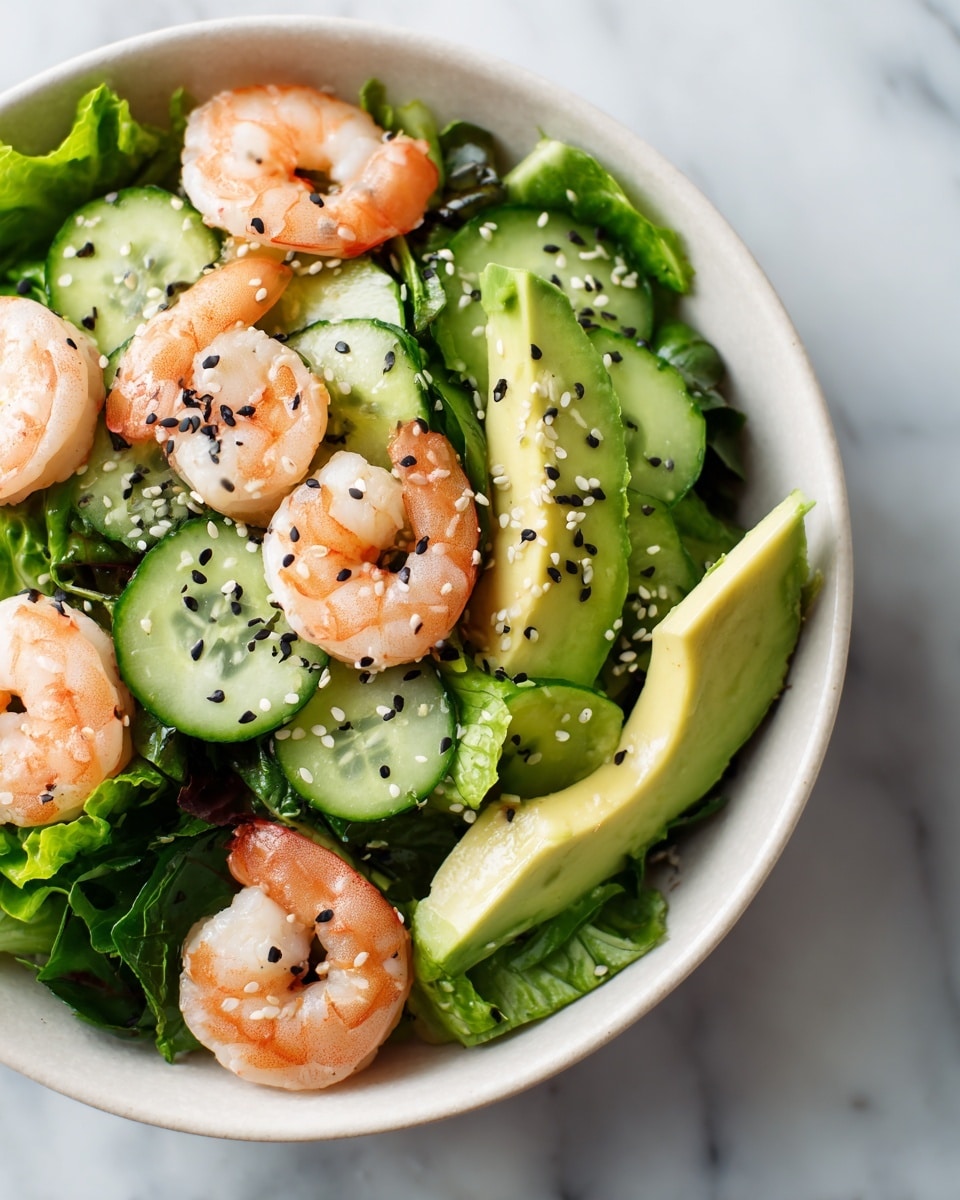 A close-up view of a shrimp salad served in a deep white bowl with a smooth round shape, placed on a white marbled surface. The salad has three main layers: the bottom layer is made of fresh bright green lettuce leaves, arranged loosely but fully covering the base; the middle layer consists of thin slices of cucumber with light green centers and darker green edges, interspersed with soft, pale green avocado slices showing creamy texture; on top, plump pink shrimp are scattered evenly across the salad, sprinkled with white and black sesame seeds adding a fine texture. The overall look is fresh, colorful, and inviting. photo taken with an iphone --ar 4:5 --v 7