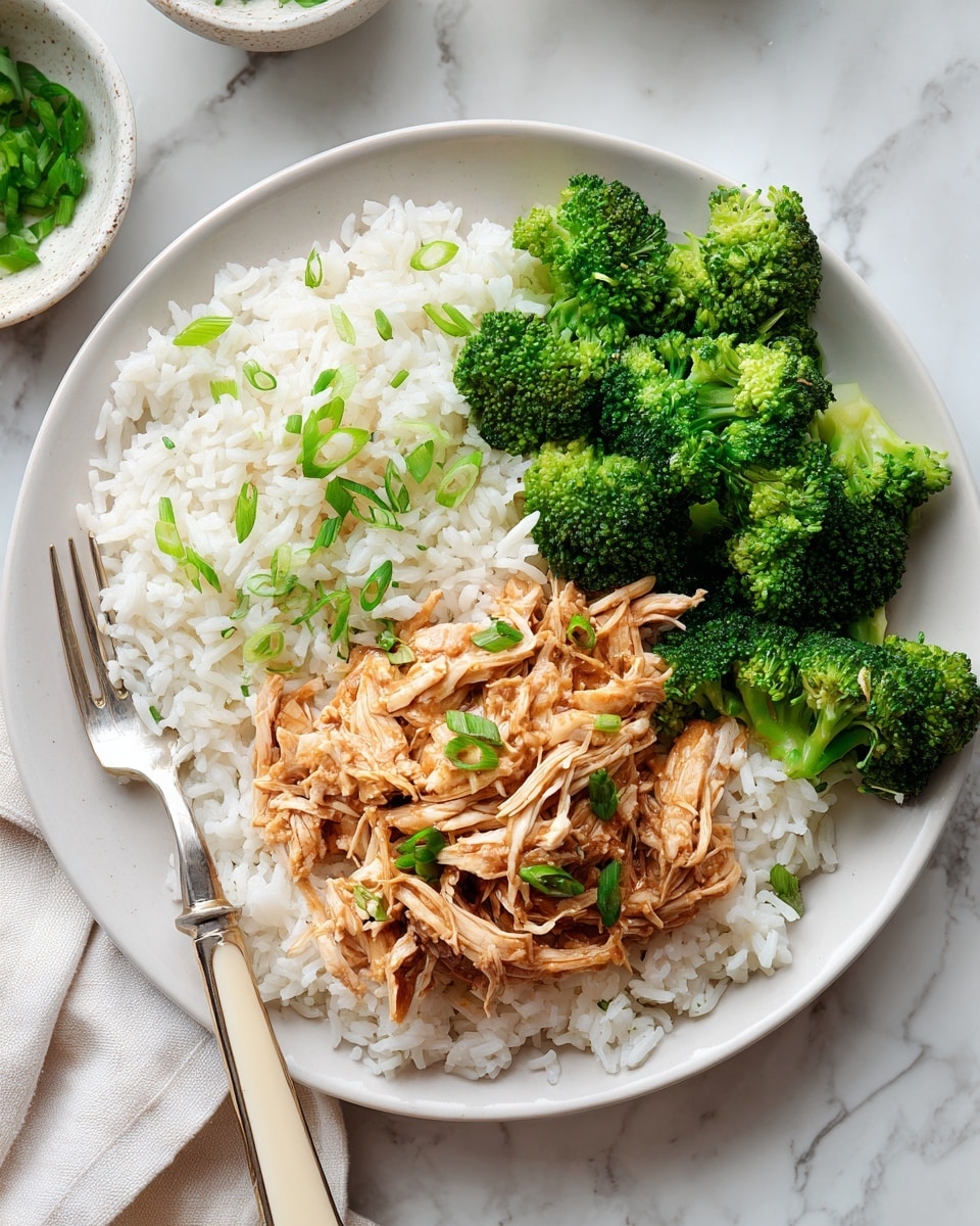 The dish is arranged in a white bowl with a base layer of plain white rice taking up most of the space. On top of the rice, there is a generous layer of shredded chicken coated in a light brown sauce, giving it a glossy and tender look. Bright green steamed broccoli florets are placed along one side of the bowl, adding a fresh contrast in color and texture. Thin slices of fresh green scallions are scattered over the chicken for garnish. The bowl sits on a white marbled surface, and there is a fork with a cream-colored handle resting on the edge of the bowl. photo taken with an iphone --ar 4:5 --v 7