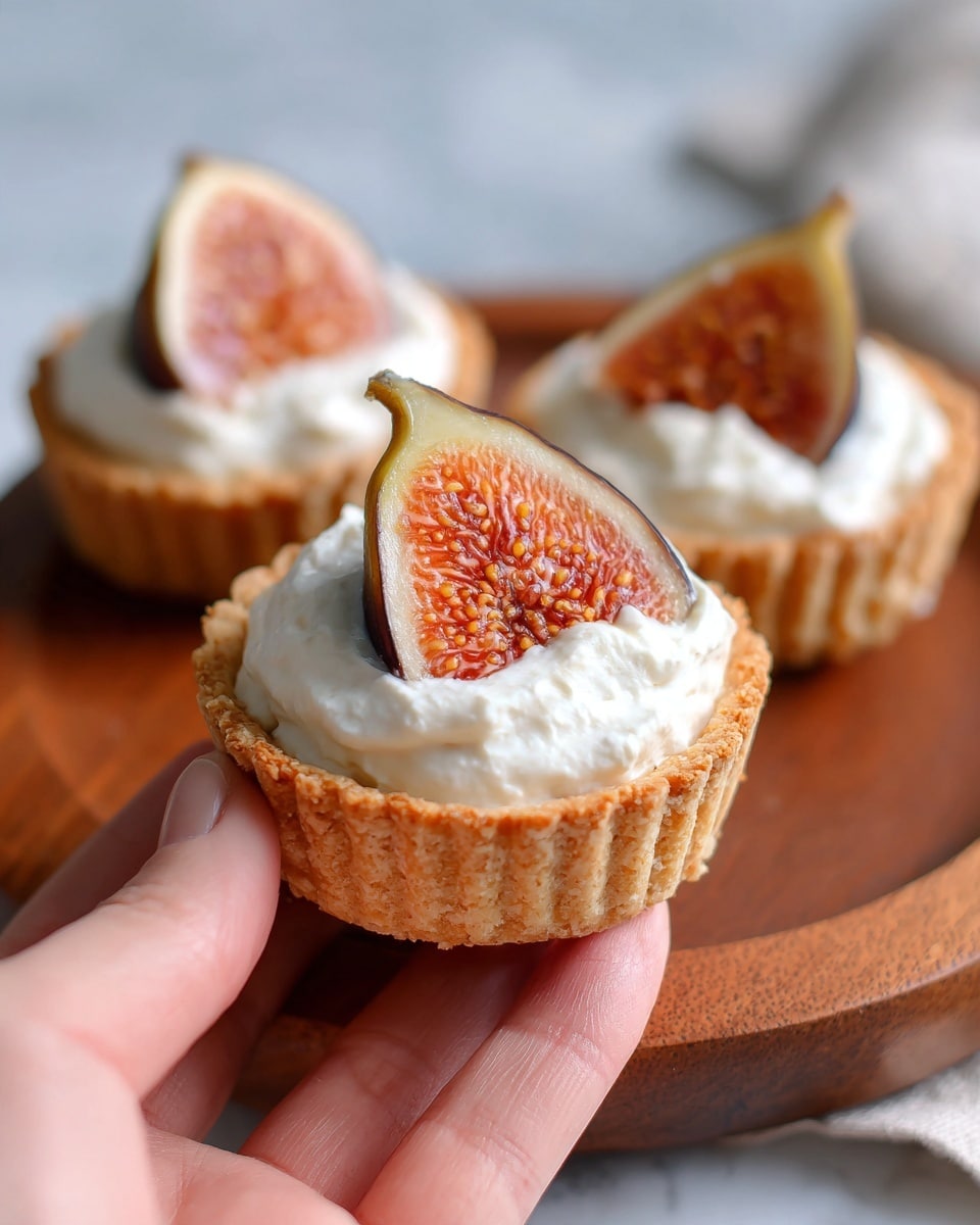 The image shows three small tartlets on a wooden board with a white marbled texture surface. Each tartlet has a crispy golden-brown pastry shell as the base. Inside the shell is a thick layer of fluffy white cream, which looks soft and smooth. On top of the cream, there is a slice of fresh fig with deep reddish-purple skin and a bright orange, seed-filled center. A woman's hand is gently holding the front tartlet, adding a natural touch to the scene. The background is softly blurred to keep the focus on the tartlets. photo taken with an iphone --ar 4:5 --v 7